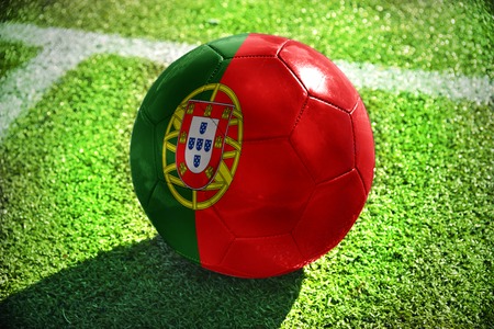 football ball with the national flag of portugal lies on the green field near the white lineの写真素材