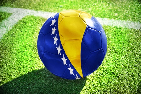 football ball with the national flag of bosnia and herzegovina lies on the green field near the white lineの写真素材