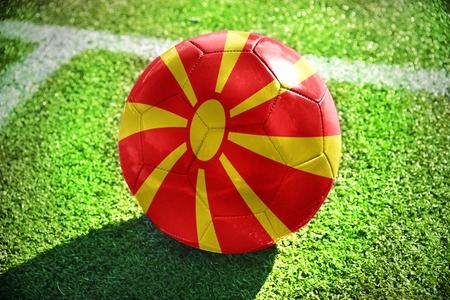 football ball with the national flag of macedonia lies on the green field near the white lineの写真素材