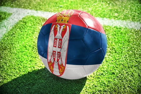 football ball with the national flag of serbia lies on the green field near the white lineの写真素材