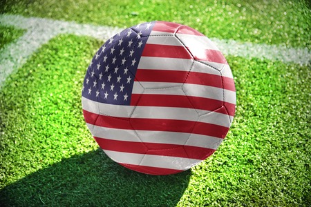 football ball with the national flag of united states of america lies on the green field near the...