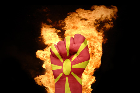 fist with the national flag of macedonia near the fire on a black backgroundの写真素材