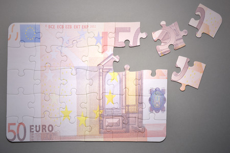 broken puzzle with the euro banknote on a gray backgroundの写真素材