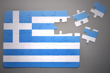 broken puzzle with the national flag of greece on a gray backgroundの写真素材