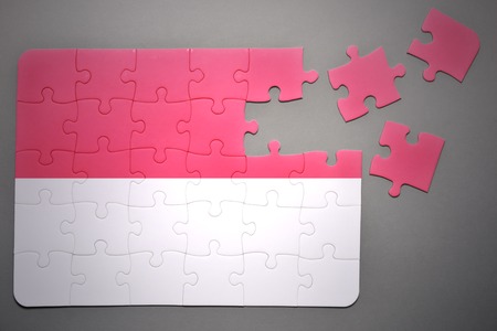 broken puzzle with the national flag of indonesia on a gray backgroundの写真素材