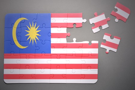broken puzzle with the national flag of malaysia on a gray backgroundの写真素材