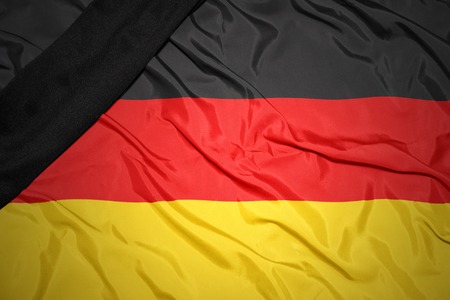 waving national flag of germany with black mourning ribbonの写真素材