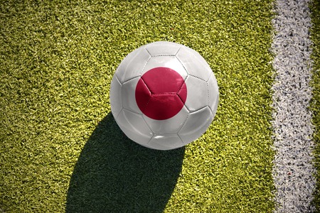 football ball with the national flag of japan lies on the green field near the white lineの写真素材
