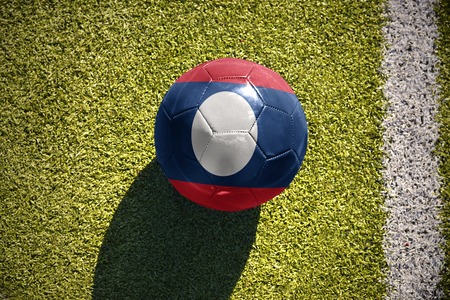 football ball with the national flag of laos lies on the green field near the white lineの写真素材