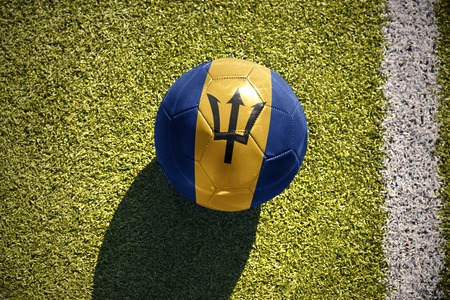 football ball with the national flag of barbados lies on the green field near the white lineの写真素材