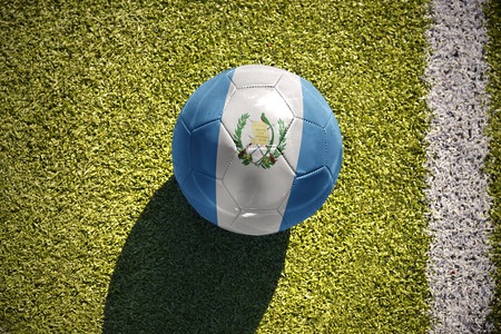football ball with the national flag of guatemala lies on the green field near the white lineの写真素材