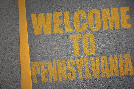 asphalt road with text welcome to pennsylvania near yellow line. conceptの写真素材