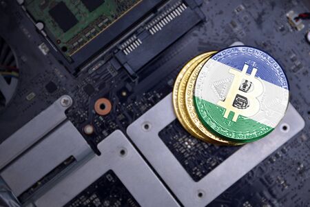 golden shining bitcoins with flag of lesotho on a computer electronic circuit board. bitcoin mining concept.の写真素材