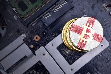 golden shining bitcoins with flag of england on a computer electronic circuit board. bitcoin mining concept.の写真素材