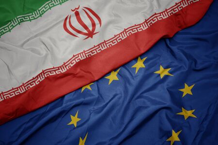 waving colorful flag of european union and flag of iran.macroの写真素材