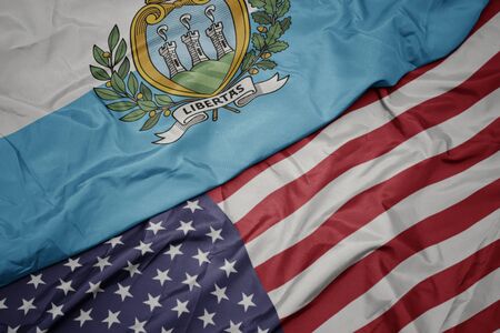 waving colorful flag of united states of america and national flag of san marino.
