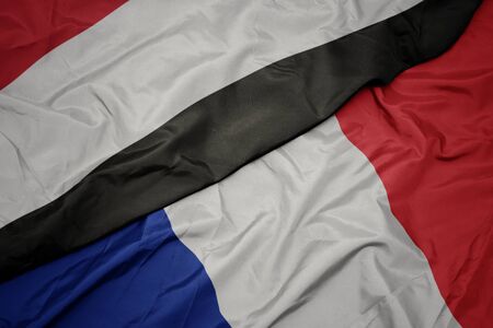 waving colorful flag of france and national flag of yemen. macro