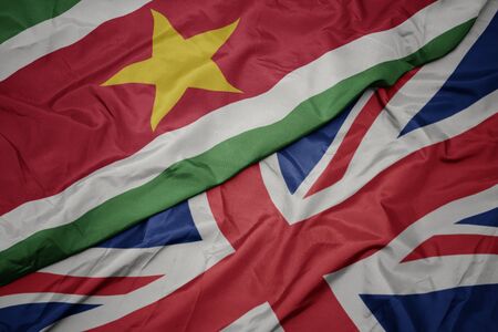 waving colorful flag of great britain and national flag of suriname. macroの写真素材