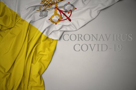 waving colorful national flag of vatican city on a gray background with text coronavirus covid-19 . concept.の写真素材