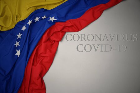 waving colorful national flag of venezuela on a gray background with text coronavirus covid-19 . concept.の写真素材