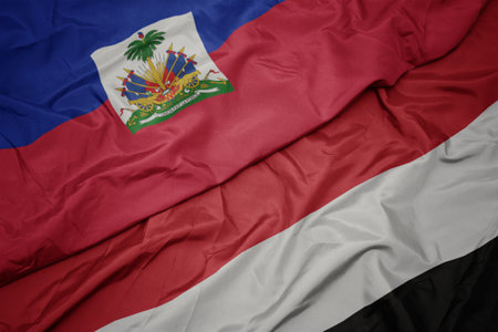 waving colorful flag of yemen and national flag of haiti. macroの写真素材