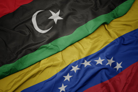 waving colorful flag of venezuela and national flag of libya. macroの写真素材