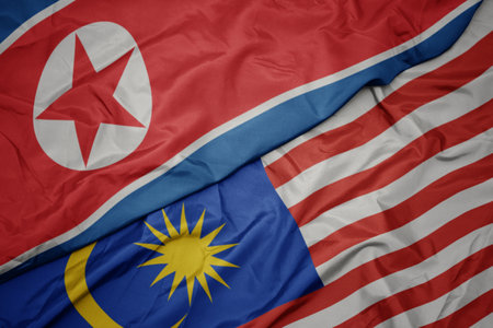 waving colorful flag of malaysia and national flag of north korea. macroの写真素材