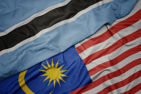waving colorful flag of malaysia and national flag of botswana. macroの写真素材