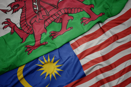 waving colorful flag of malaysia and national flag of wales. macroの写真素材