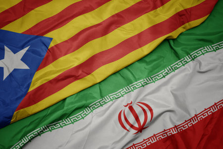 waving colorful flag of iran and national flag of catalonia. macro