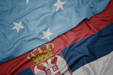 waving colorful flag of serbia and national flag of Federated States of Micronesia . macro