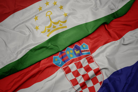 waving colorful flag of croatia and national flag of tajikistan. macro