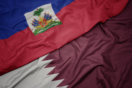 waving colorful flag of qatar and national flag of haiti. macroの写真素材