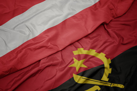 waving colorful flag of angola and national flag of austria. macroの写真素材