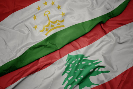 waving colorful flag of lebanon and national flag of tajikistan. macroの写真素材