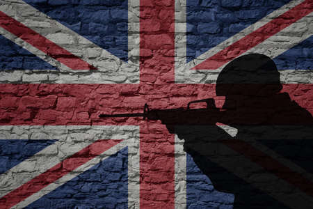 Soldier silhouette on the old brick wall with flag of great britain country. Military strength