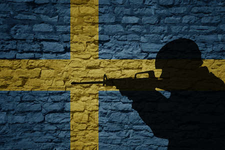 Soldier silhouette on the old brick wall with flag of sweden country. Military strengthの写真素材