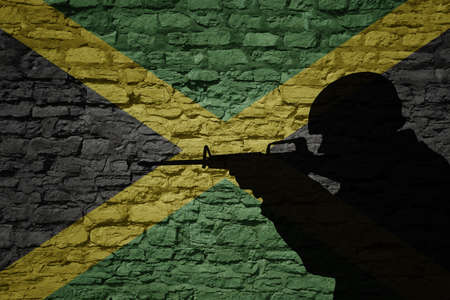 Soldier silhouette on the old brick wall with flag of jamaica country. Military strength