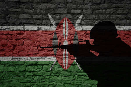 Soldier silhouette on the old brick wall with flag of kenya country. Military strengthの写真素材