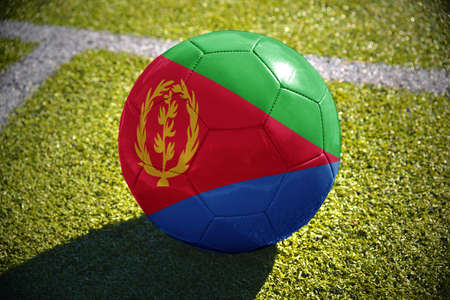 football ball with the national flag of eritrea lies on the green field near the white lineの写真素材