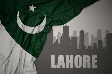 abstract silhouette of the city with text Lahore near waving colorful national flag of pakistan on a...