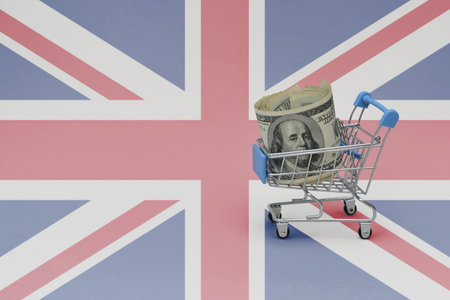 Metal shopping basket with big dollar money banknote on the national flag of great britain background. consumer basket concept. 3d illustrationの写真素材