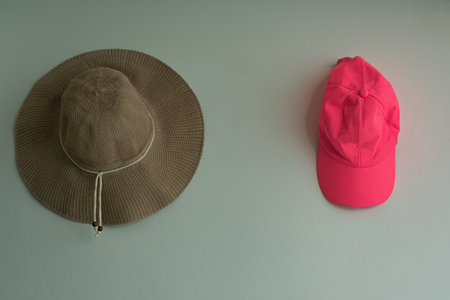 A colorful cap and a straw hat, on the wall.の写真素材
