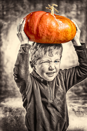 Portrait of little boy making a face with heavy orange pumpkin hat.の写真素材