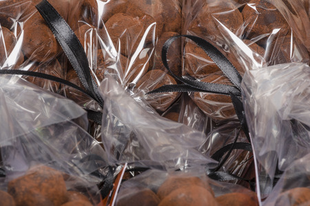 Closeup on Christmas chocolate truffles stacked in luxury plastic bags with black ribbonsの写真素材