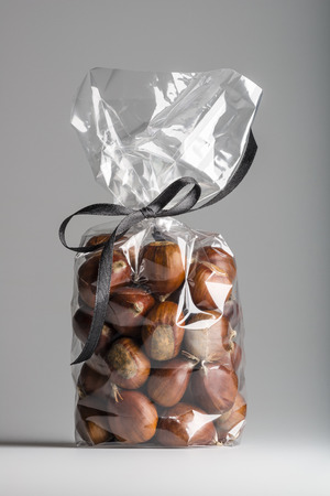 Beautiful and delicious sweet chestnuts bag with elegant black ribbon isolated on grey background. Shooting in studio.の写真素材