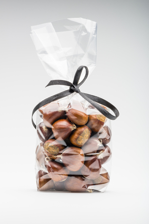 Beautiful  fresh chestnuts bag with elegant black ribbon isolated on white background. Shooting in studio.の写真素材