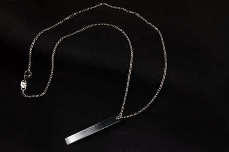 Silver jewelry chain bracelet necklace isolated on black engraving plateの写真素材