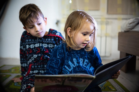 Brother and sister read book in pyjamas bare feet evening sleep family