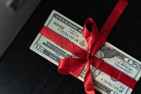 Money as a birthday present gift with red ribbon, dollar presentの写真素材